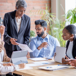 An older colleague guiding younger team members, reviewing a document together in a collaborative meeting.